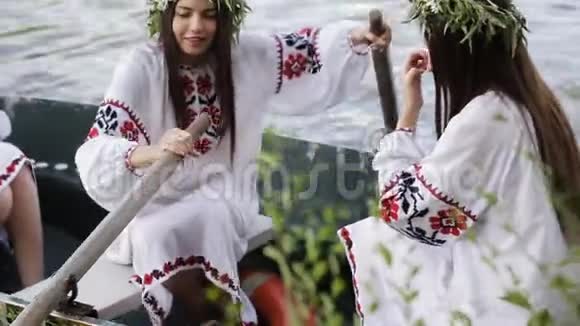 三个女孩穿着斯拉夫民族服装漂浮在河上的一艘船上戴花环的女孩笑得很开心国家视频的预览图