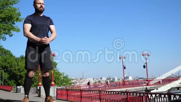 留胡子的人在早上的户外锻炼中蹲着桥附近的健身训练视频的预览图