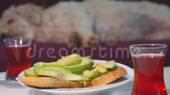 女人早餐吃鳄梨三明治和红茶视频的预览图