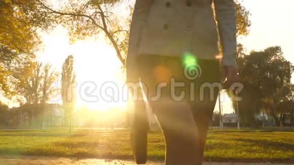 商务女性的美腿走在人行道上商务女性穿裙子在公园里散步穿着美丽的光线视频的预览图
