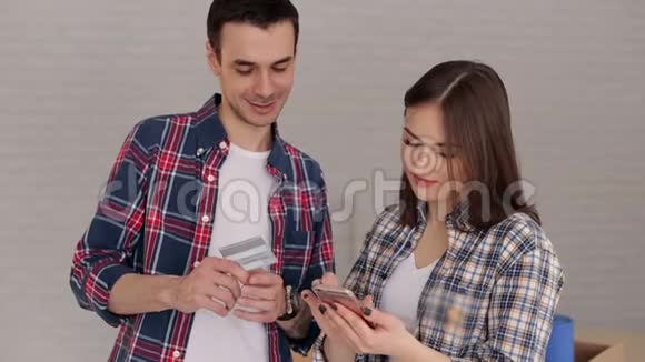 夫妇用塑料信用卡和智能手机支付购买费用视频的预览图