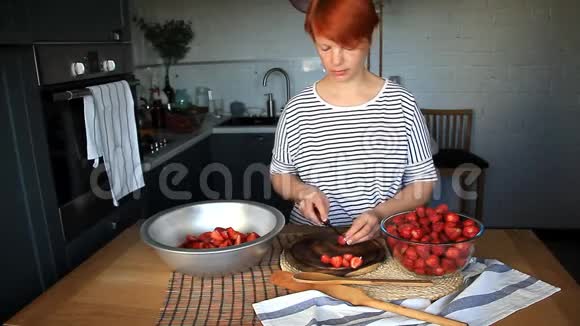 年轻女子切新鲜成熟的草莓做果酱视频的预览图