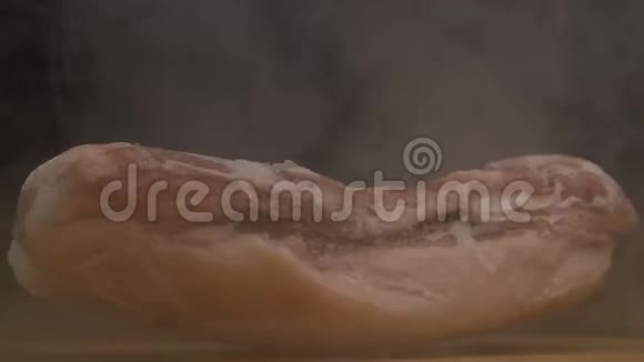 一块黑色背景的冷冻旋转猪肉霜冻的新鲜和烟雾来自肉特写视频的预览图