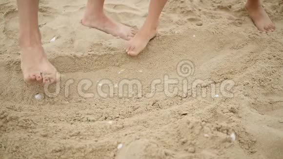 女人和孩子在沙滩上玩沙子留下脚印一个女人和一个小孩的腿特写视频的预览图