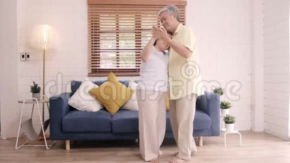 亚洲老年夫妇一起跳舞在家客厅听音乐甜蜜的夫妇享受爱情的时刻视频的预览图