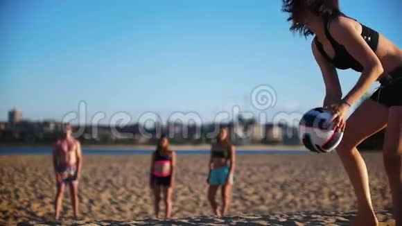 布鲁内特女孩从地上捡起球边打沙滩排球边朝球员扔过去视频的预览图