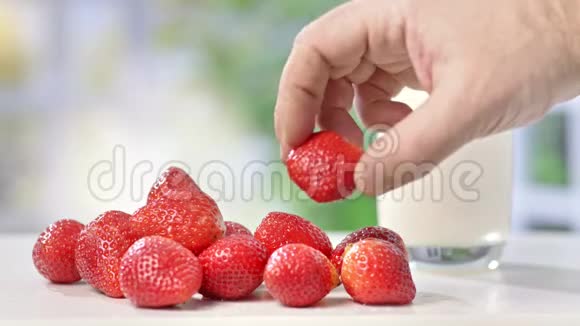 夏季成熟的雄性手把新鲜草莓一个接一个地放在桌上视频的预览图