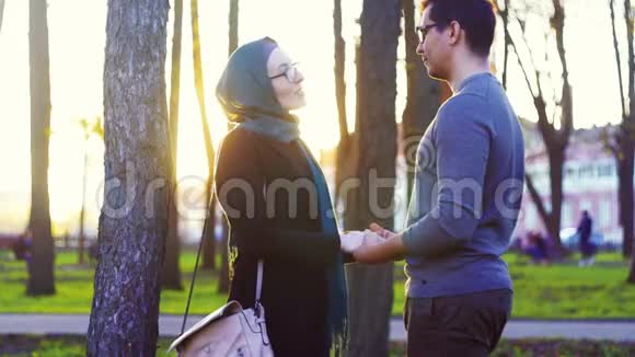 戴头巾的男人和女人在公园里牵手视频的预览图
