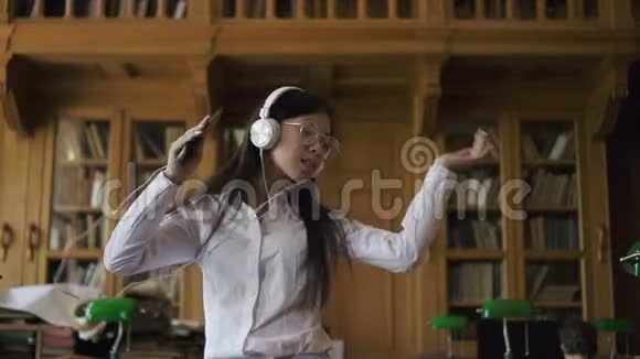 美丽的亚洲女人穿着白衬衫戴着圆眼镜听音乐视频的预览图
