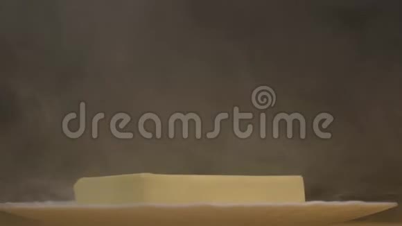 从油中旋转的盘子上的黄油是霜冻的新鲜和烟雾特写黑色背景4K视频的预览图
