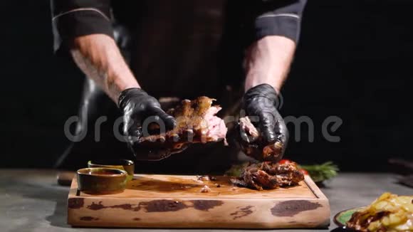 男性双手戴着黑色橡胶手套撕裂多汁的烤肋骨紧紧地紧紧地抓住慢动作视频的预览图