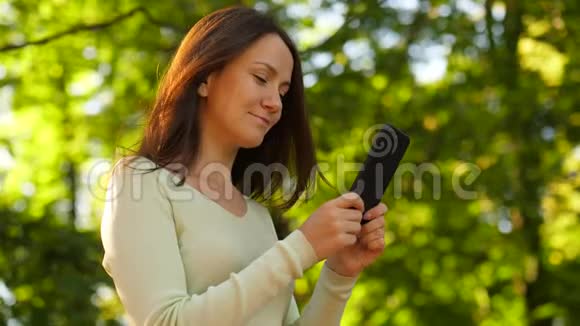 漂亮的女人用智能手机触摸长发视频的预览图