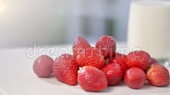 牛奶背景玻璃中白色桌面上鲜有有机草莓的特写视频的预览图