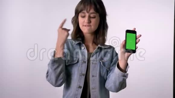 年轻的黑发女孩在智能手机绿色屏幕上移动交流概念白色背景视频的预览图