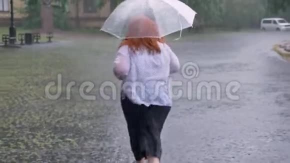 胖姜女的剪影在雨中跑在公园里撑着伞后景视频的预览图