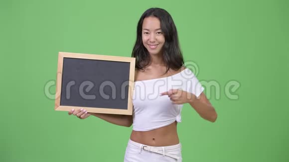 年轻快乐美丽多民族的女人拿着黑板竖起大拇指视频的预览图