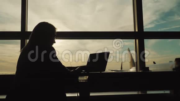 西装商务女性剪影在机场候机楼用笔记本电脑工作视频的预览图