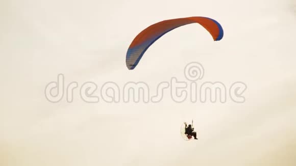 滑翔伞男子是滑翔伞在城市与金色日落天空背景视频的预览图