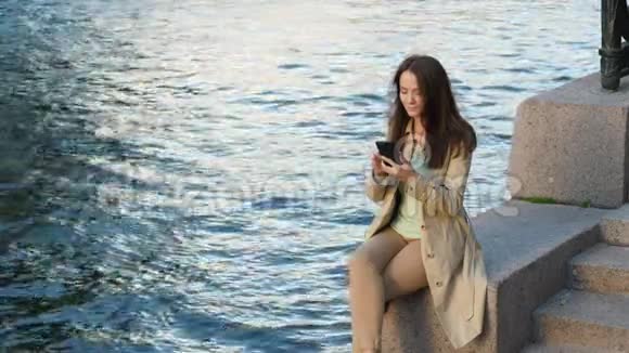 水堤附近智能手机聊天的漂亮女孩视频的预览图