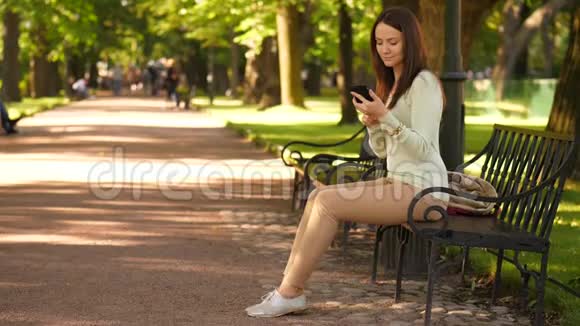 商务女性使用智能手机坐在夏季公园视频的预览图