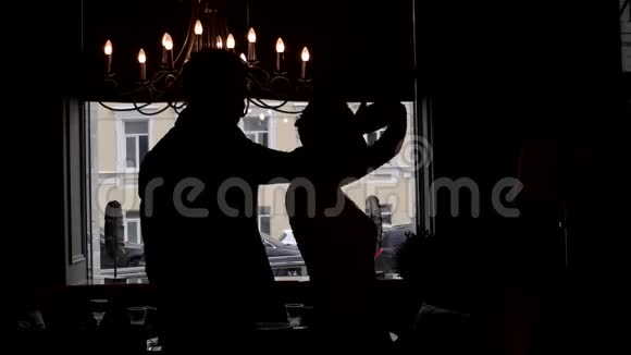 年轻的新婚夫妇在窗前的剪影中翩翩起舞视频的预览图