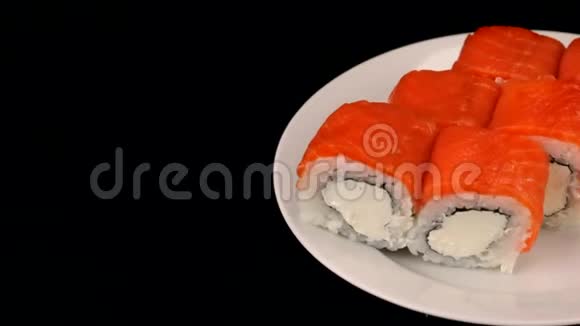美味的费城卷在黑色背景的盘子上旋转日本料理视频的预览图