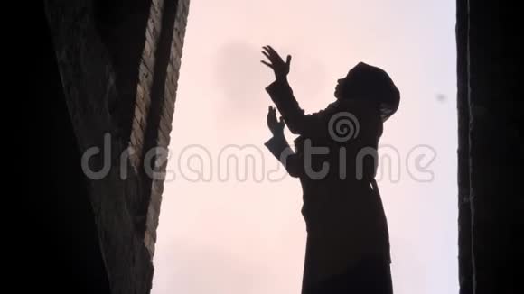 年轻的穆斯林妇女戴着头巾举起双手向天空祈祷在废弃的大楼里祈祷吓坏了视频的预览图