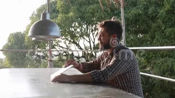 一个长胡子的帅哥打开笔记本电脑开始户外工作视频的预览图