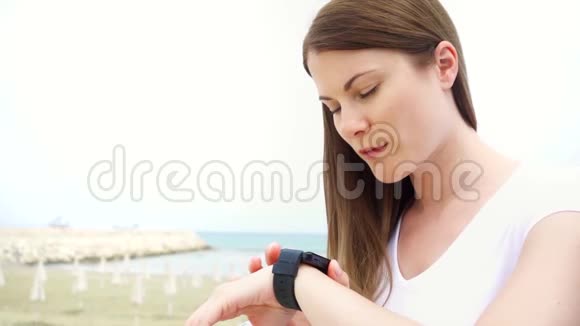 年轻女子独自在海滩上使用智能手表女性通过智能手表慢动作口述信息视频的预览图