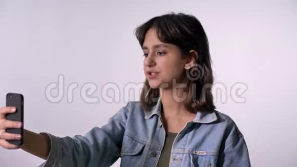 年轻的黑发女孩有视频通话智能手机再见手势沟通概念白色背景视频的预览图
