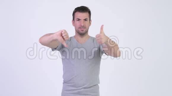 年轻快乐的西班牙男人在竖起大拇指和竖起大拇指之间做出选择视频的预览图