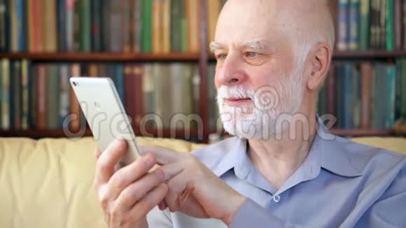 老人在家放松阅读平板电脑上享受退休的新闻背景书架视频的预览图