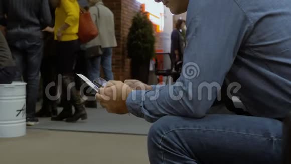 一个男性坐在队列中使用智能手机解决他的事务视频的预览图