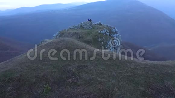 徒步旅行的一群朋友在山崖上放松空中4k无人机电影视频的预览图