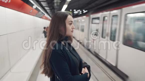 年轻女孩站在站台上等待火车到达视频的预览图