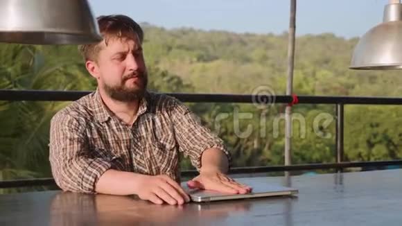 一个长胡子的帅哥打开笔记本电脑开始户外工作视频的预览图