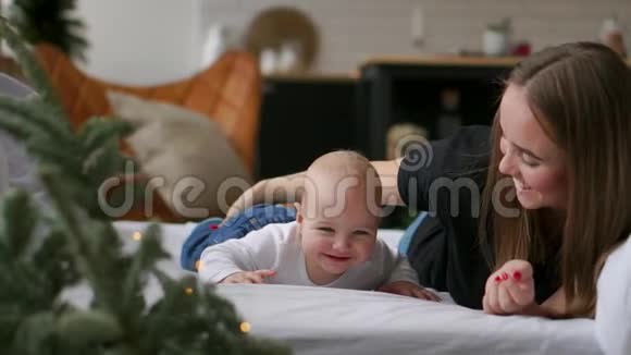 年轻的母亲拥抱她新生的孩子妈妈在照顾宝宝女人和新出生的男孩在白色的卧室里放松家庭视频的预览图