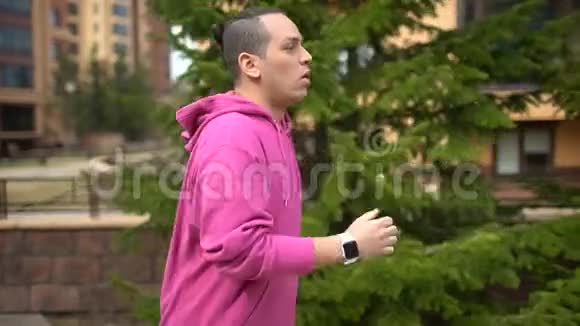 年轻的帅哥在公园晨跑时使用智能手表拉丁嘻哈跑者视频的预览图