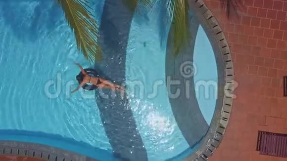 女孩趴在游泳池游泳圈上视频的预览图