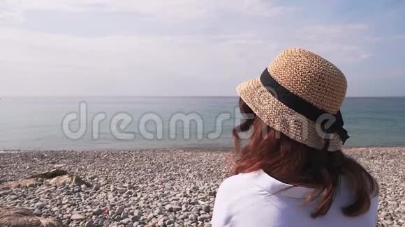 在鹅卵石海滩上看海的女人后景视频的预览图