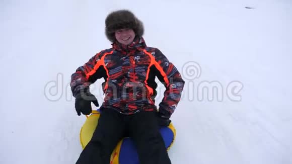 人在雪中滑动在充气雪管和波浪手快乐的人在雪橇上滑过雪男人在玩游戏视频的预览图
