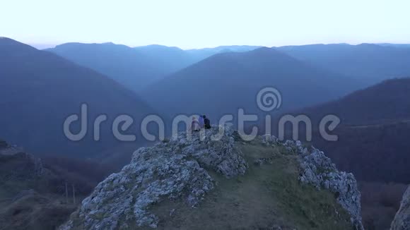 徒步旅行的一群朋友在山崖上放松空中4k无人机电影视频的预览图