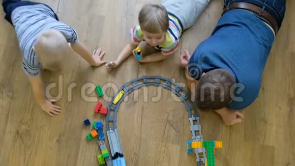家庭观念孩子们和爸爸在木地板上玩火车有儿子的父亲直接上图视频的预览图