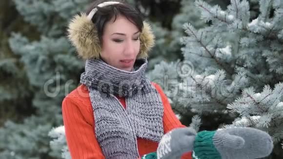 冬天森林里穿着毛皮手套的女人把手举起来美丽的风景雪杉树视频的预览图