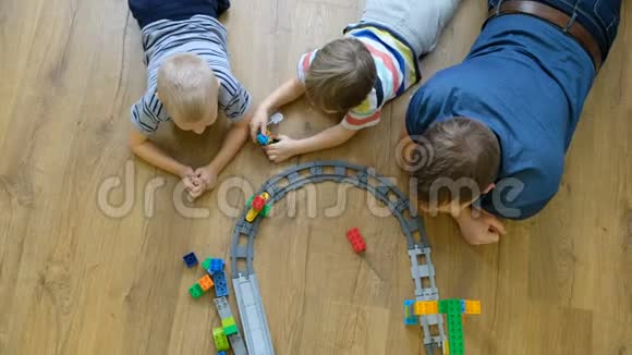 家庭观念孩子们和爸爸在木地板上玩火车有儿子的父亲直接上图视频的预览图