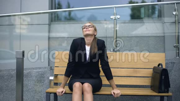在紧张的工作前漂亮的商务小姐坐在长凳上欣赏着早晨视频的预览图