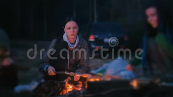 两个女人在火上煎香肠一家人晚上露营视频的预览图