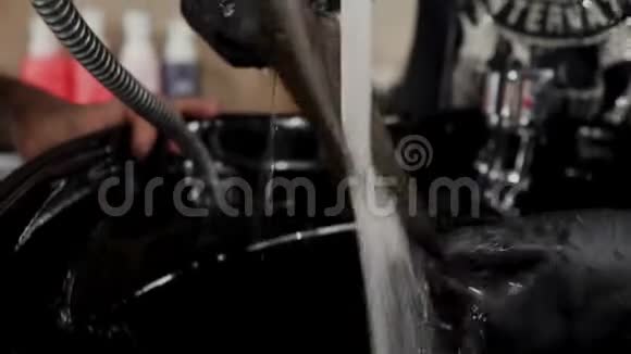 理发师在水龙头下洗一缕头发以延长头发4K视频的预览图