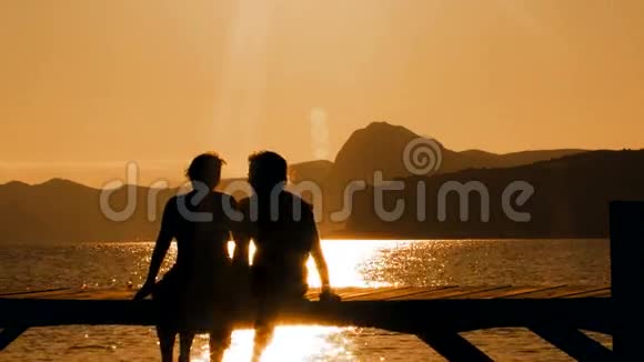 日落时分坐在桥上的男人和女人视频的预览图