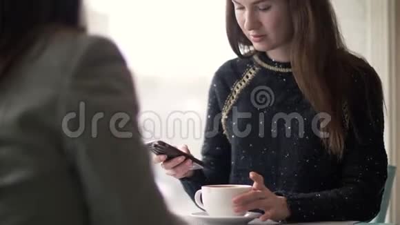 在咖啡馆里和朋友见面时女人在餐桌上用手机视频的预览图